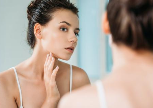 woman looking closely at her skin in the mirror