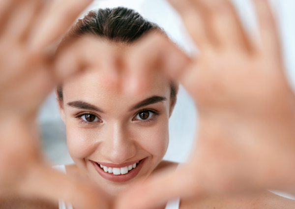  Woman smiling at the camera, making a love heart with her hands