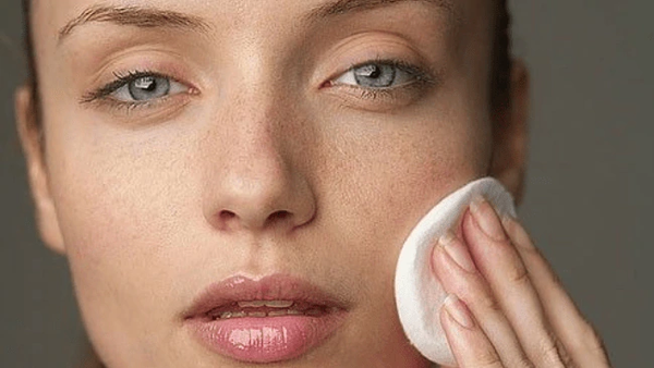 Woman with clean skin removing makeup with a cotton round